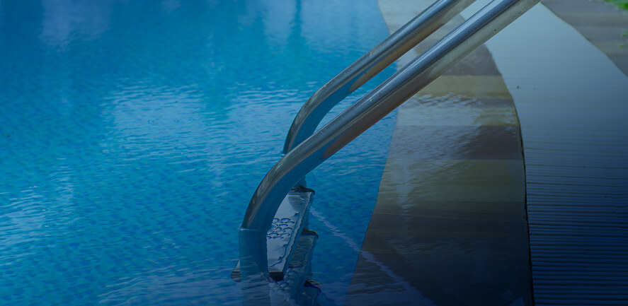 edge of a swimming pool with ladder descending into the water 